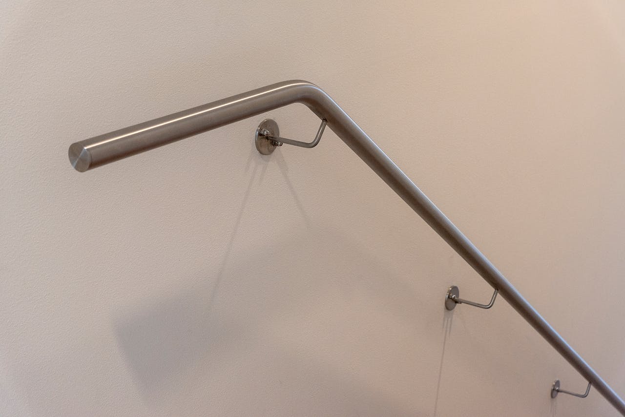 Close-up of a sleek stainless steel railing on a beige wall, ideal for modern interiors.